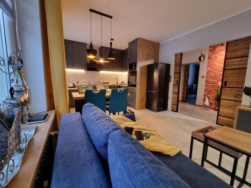 a living room with a blue couch and a kitchen at Apartament LuxLoft in Piechowice