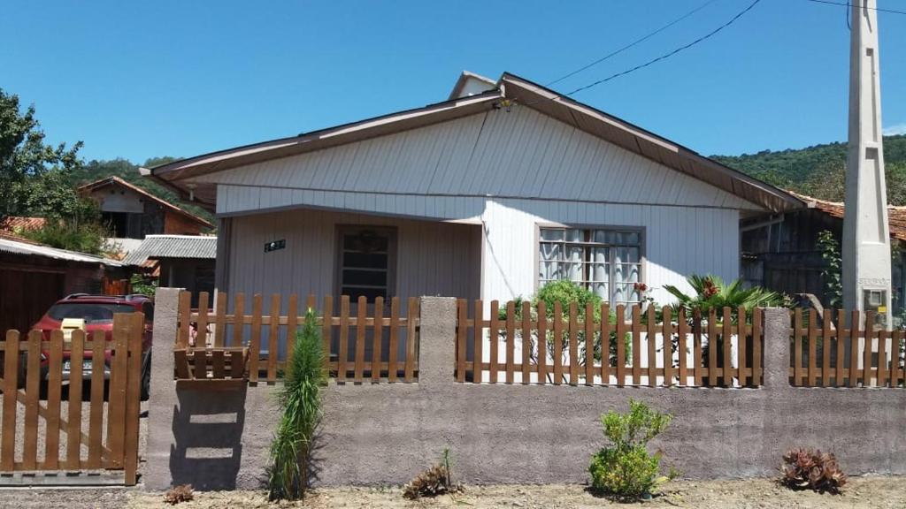 una casa con una valla de madera delante de ella en Casa de temporada da vovó, en Urubici