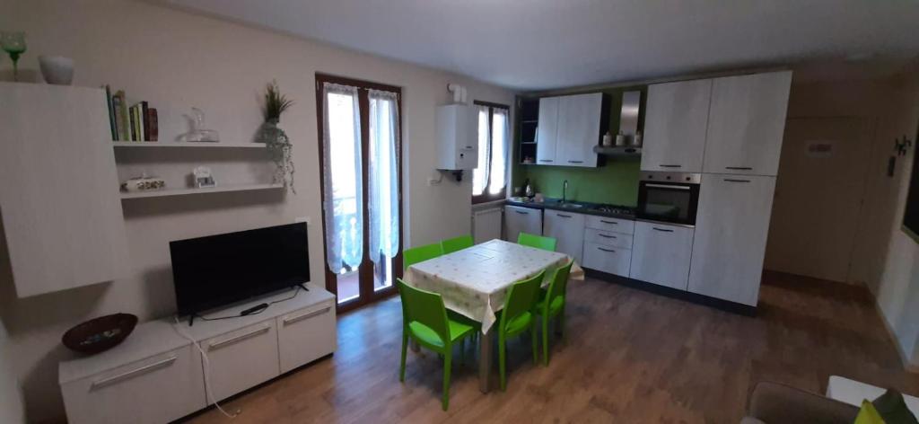 a kitchen with a table and green chairs in it at Casa Ester in Serina