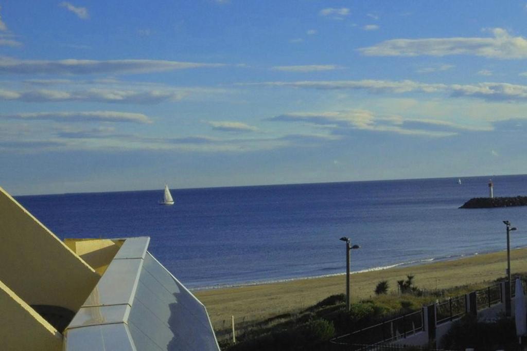 a view of a beach with a sail boat in the water at Cap d'Agde Naturist Héliopolis O 33 in Cap d'Agde