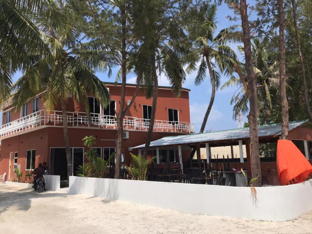 a building on the beach with palm trees at Merijaan Maldives in Maafushi