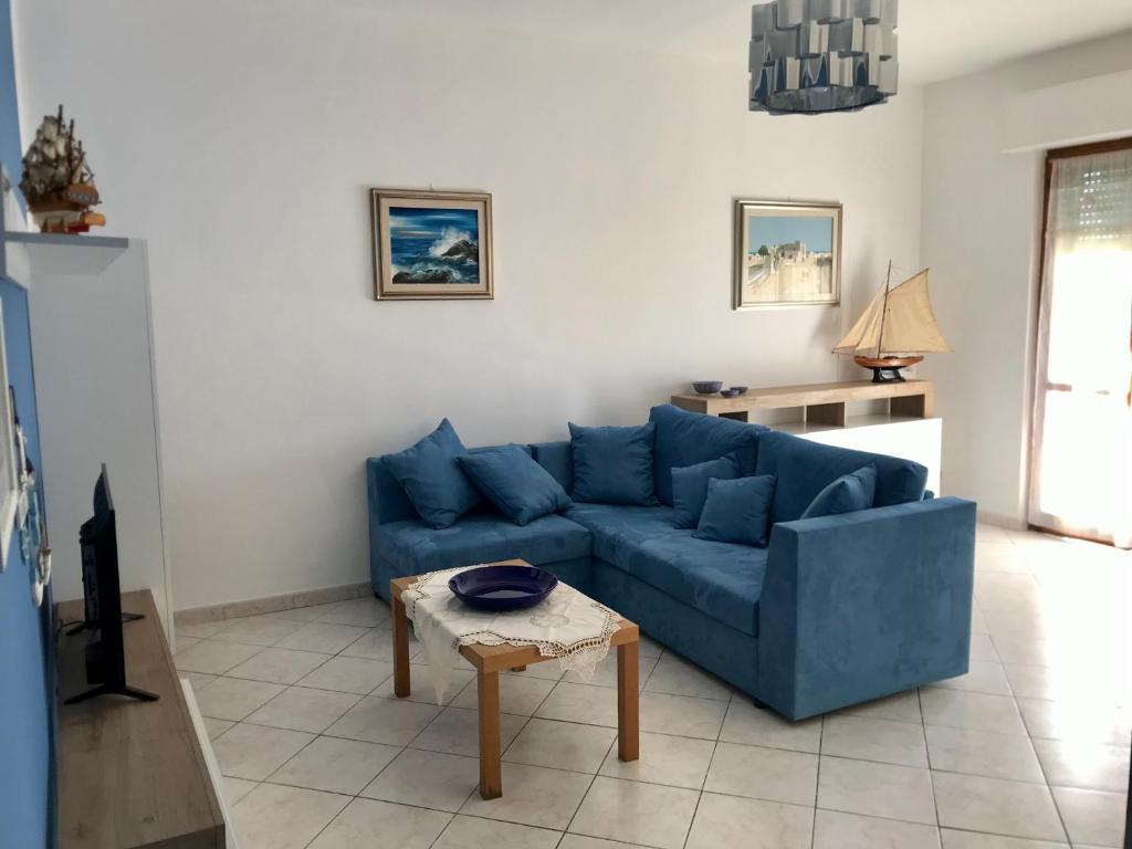 un soggiorno con divano blu e tavolo di Attico centralissimo e vicino al mare ad Alghero
