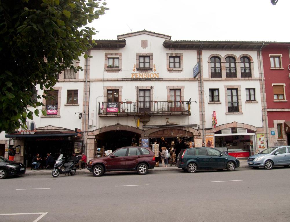 un gran edificio blanco con coches estacionados frente a él en Pensión Plaza del Ayuntamiento en Cangas de Onís