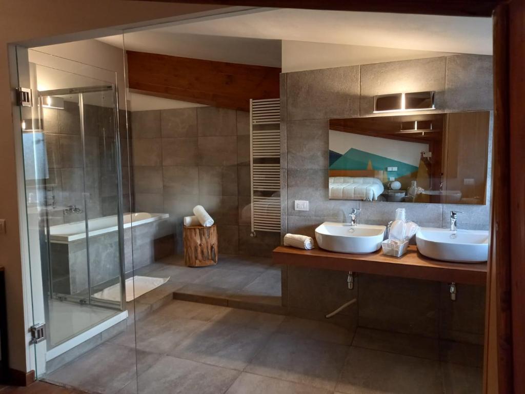 łazienka z 2 umywalkami, prysznicem i wanną w obiekcie Chalet Lago w mieście Taverna