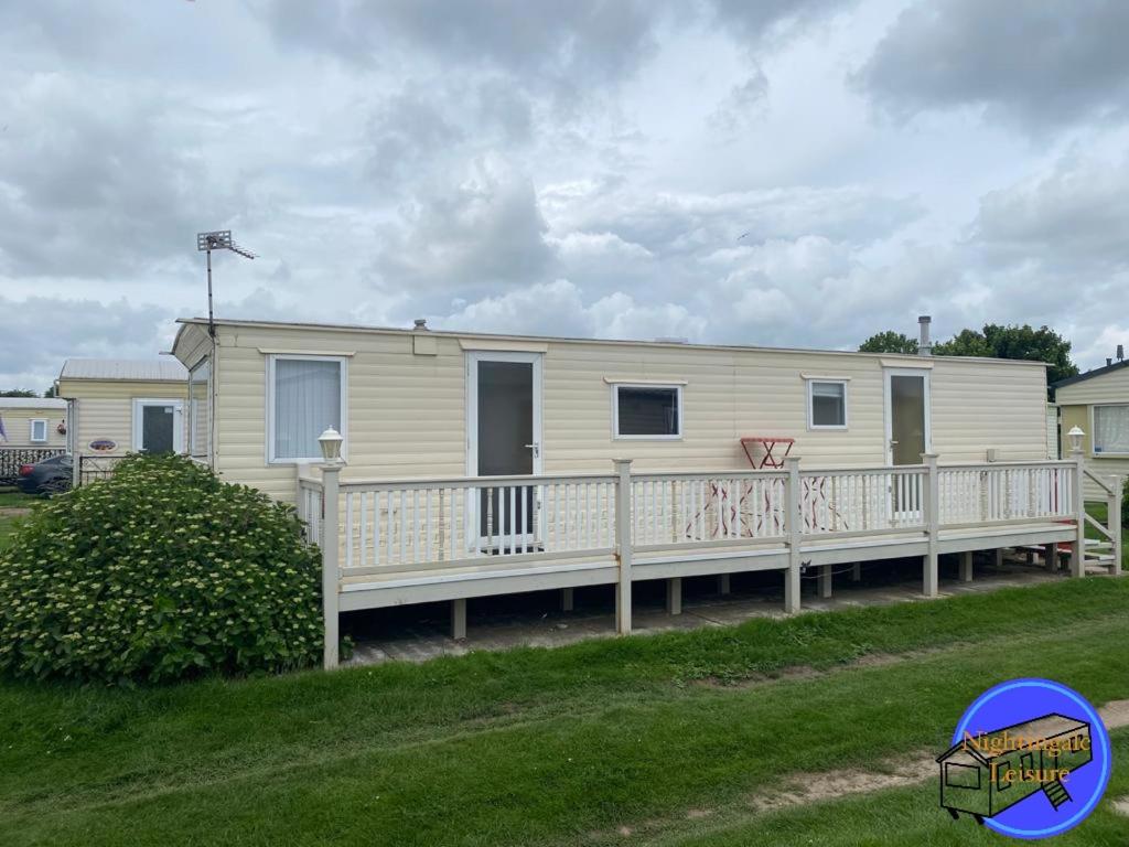 Ce mobile home dispose d'une terrasse couverte et d'un panier de basket. dans l'établissement Chapel St Leonards Caravan, à Chapel St. Leonards