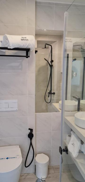 a white bathroom with a toilet and a shower at Hotel Mar Bravo in Nazaré