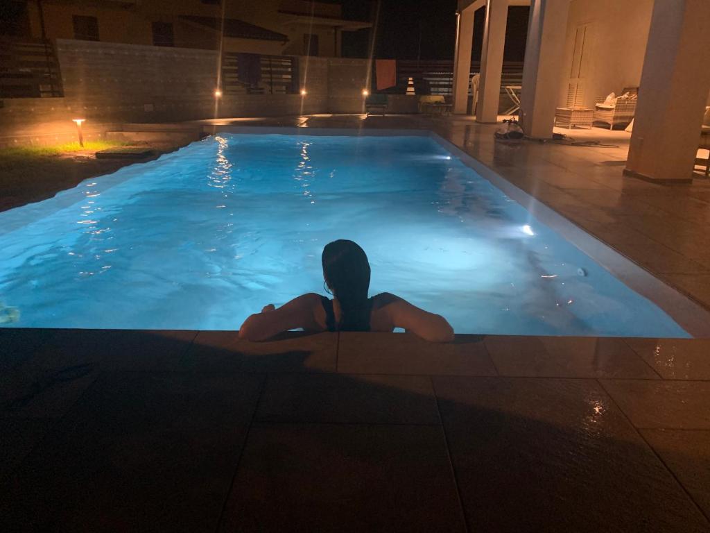 a woman laying in a swimming pool at night at B&B Melissa in Noto