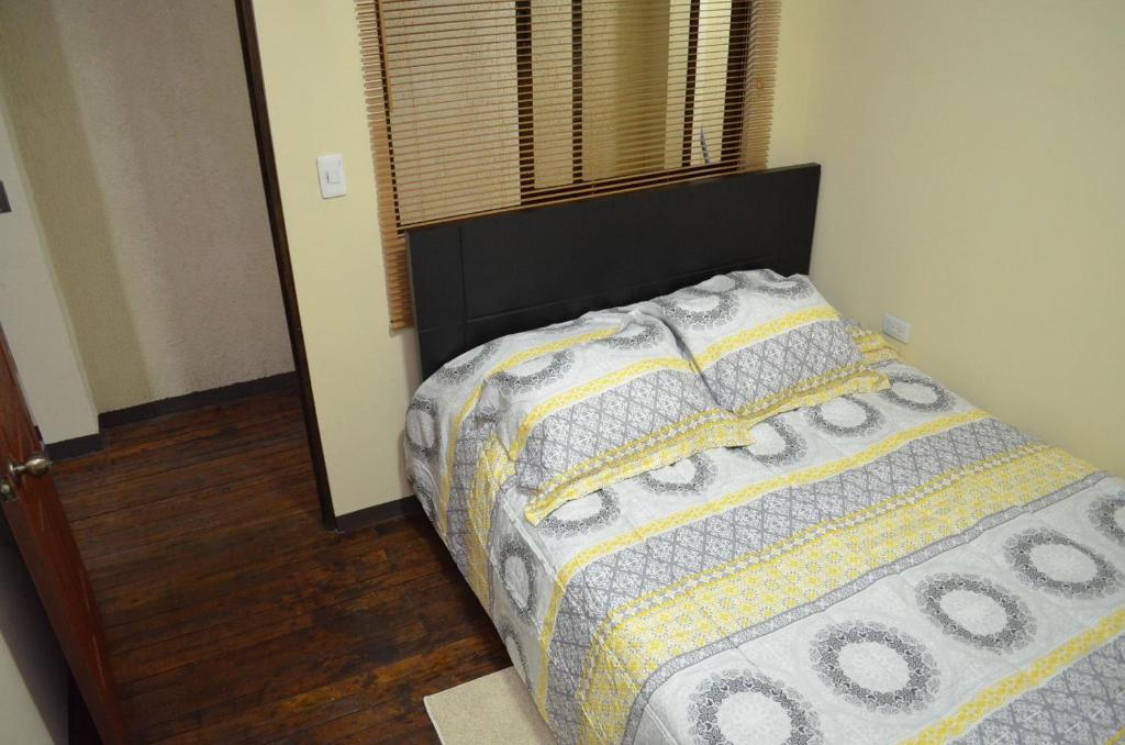 a bedroom with a bed with a comforter and a window at #3 Private room Close to Airport in Alajuela