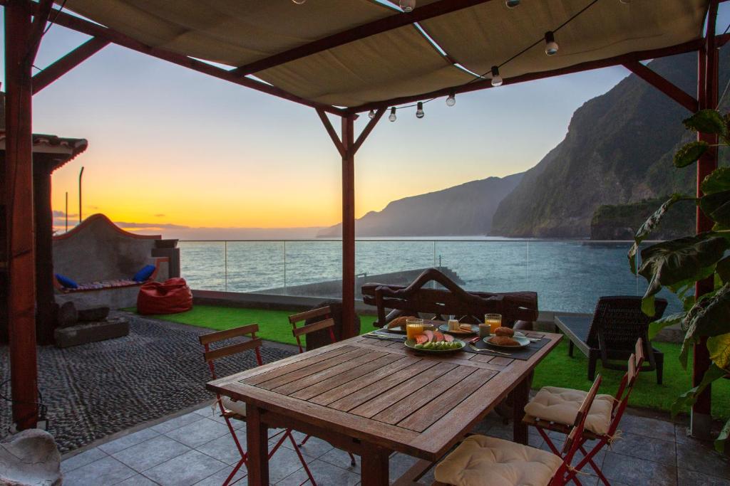 a table on a patio with a view of the ocean at Madeira Black Sand House by Stay Madeira Island in Seixal