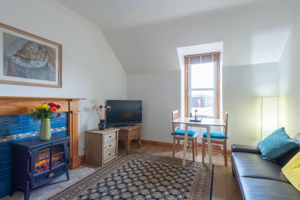 ein Wohnzimmer mit einem Sofa und einem Kamin in der Unterkunft The 'Fairy Hill' Apartment in Inverness