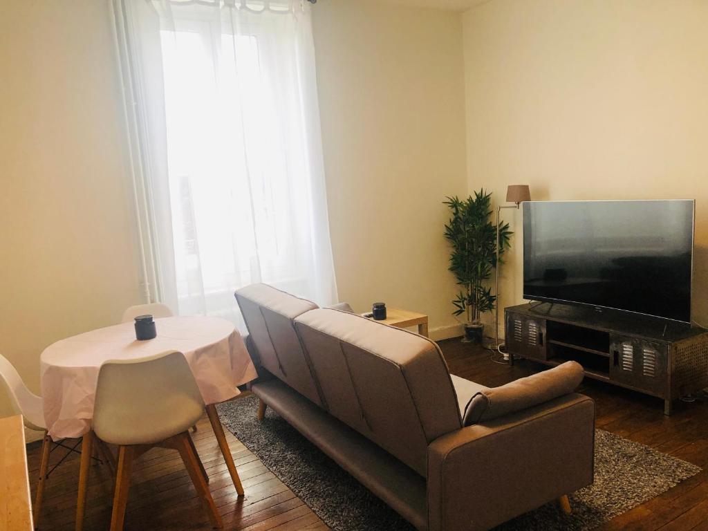 sala de estar con sofá, TV y mesa en Appartement T2 proche gare - DABNB en Limoges
