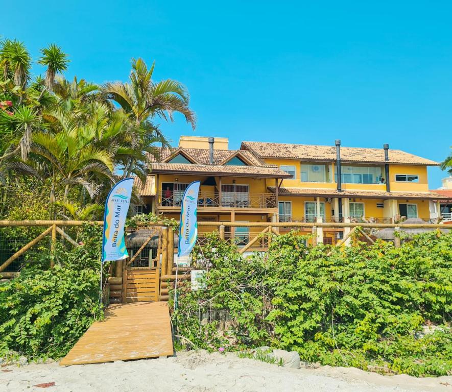 una casa en la playa con un paseo marítimo de madera en Apart Hotel Beira do Mar en Florianópolis