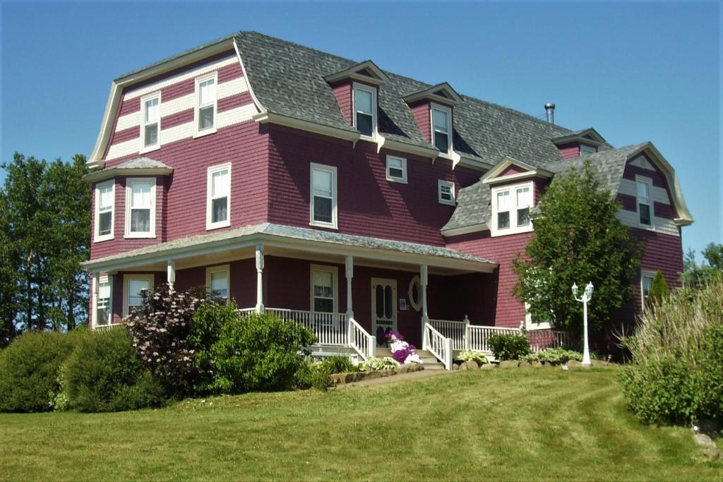 a large red house with a gambrel roof at Hillcrest Hall Country Inn in Port Hood