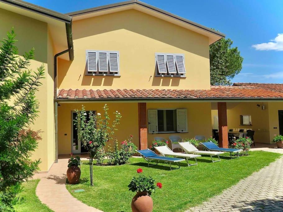 ein Haus mit einem Garten, in dem blaue Stühle stehen in der Unterkunft Villa Parenti in Lucca