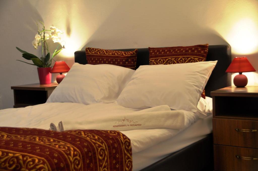 1 cama con sábanas y almohadas blancas y 2 lámparas en Green Terrace Apartment Budapest, en Budapest