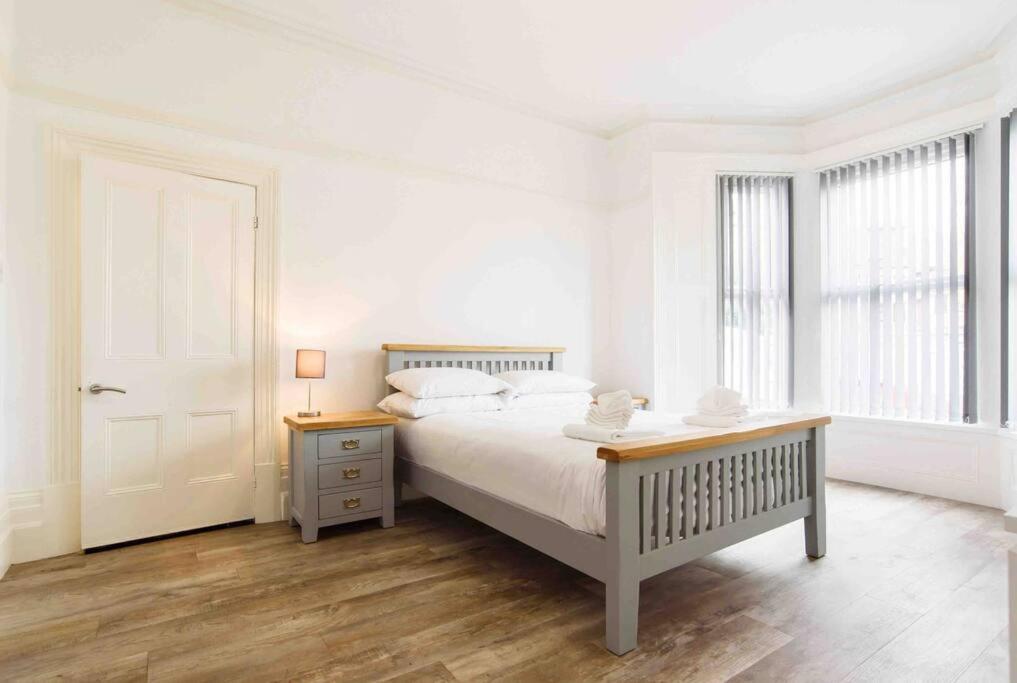 a white bedroom with a bed and a table at Caerau Gardens in Newport