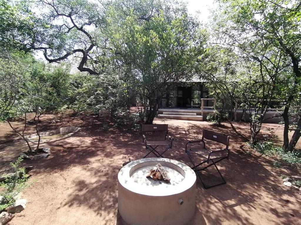 2 chaises et une fontaine dans une cour arborée dans l'établissement Amukela Kaya, à Hoedspruit