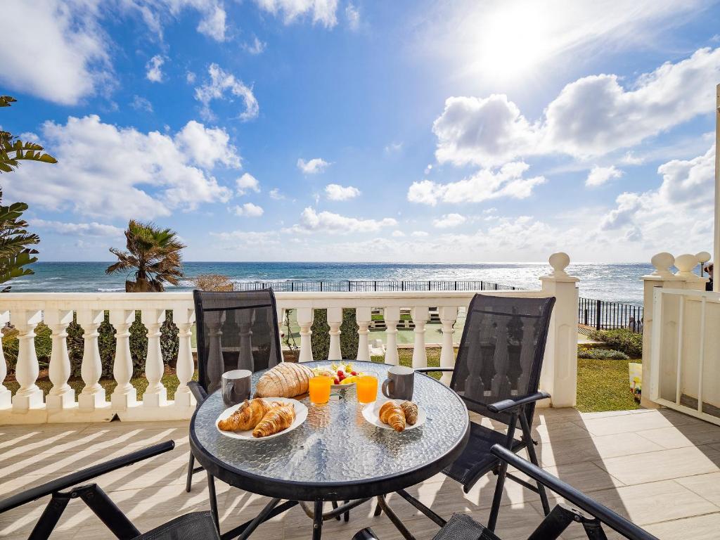 a table with bread and oranges on a balcony with the beach at Apartment on Beach Mijas in Mijas Costa