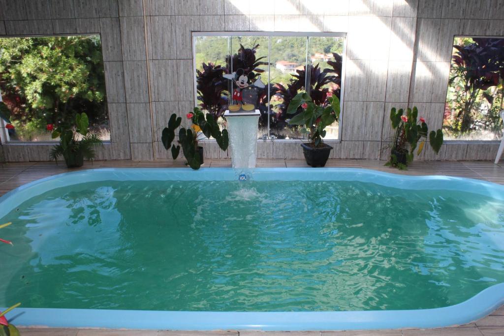 a swimming pool with a fountain in a yard at Pousada Aconchego da Valdirene in Lavras Novas