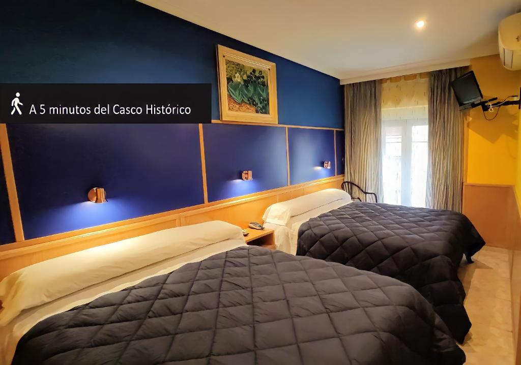 Habitación de hotel con 2 camas y pared azul en Trípolis Toledo, en Toledo