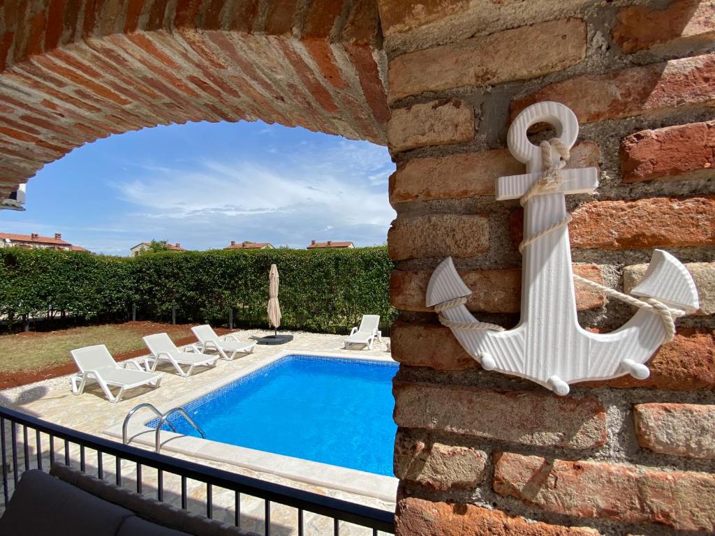 una piscina con ancla náutica en una pared de ladrillo en Paradise Villa Cassonni Istria 4 Stars, en Butkovići