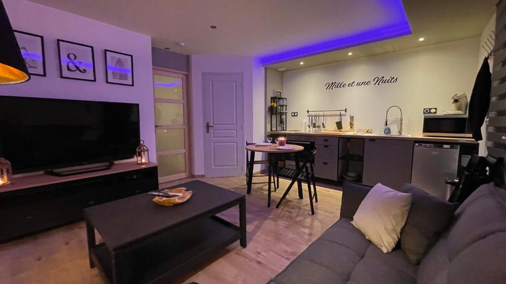 a living room with a couch and a kitchen at Mille et une nuit, appartement classé 3 étoiles en RDC avec exterieur et parking in Dole