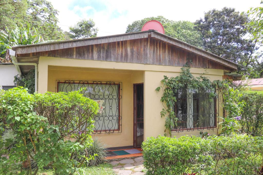 une petite maison jaune avec un portail et des arbres dans l'établissement Casa Copalchi, à Monteverde Costa Rica