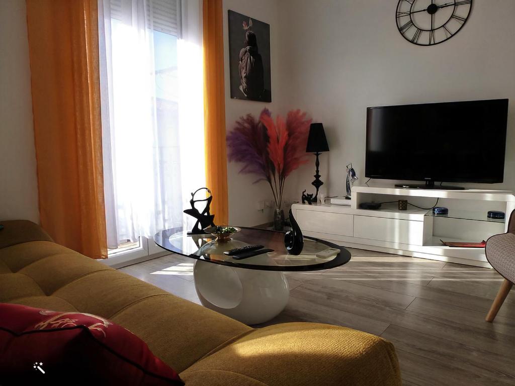 sala de estar con sofá, mesa y TV en Chic et douillet en Perpiñán