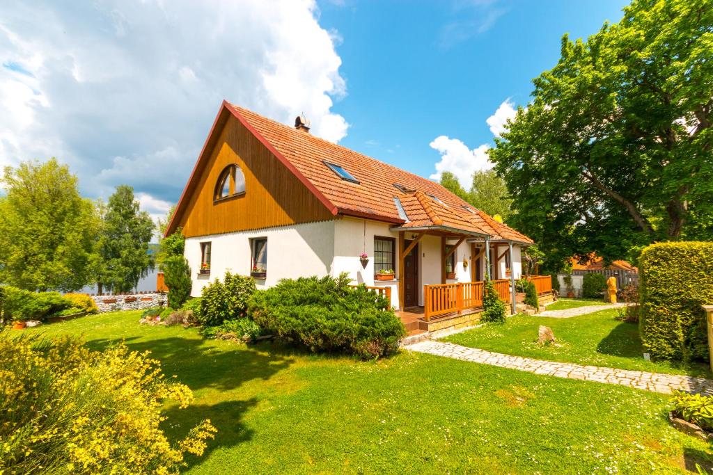 ein Haus mit rotem Dach auf einem grünen Hof in der Unterkunft Apartments U Jezera Černá in Černá v Pošumaví