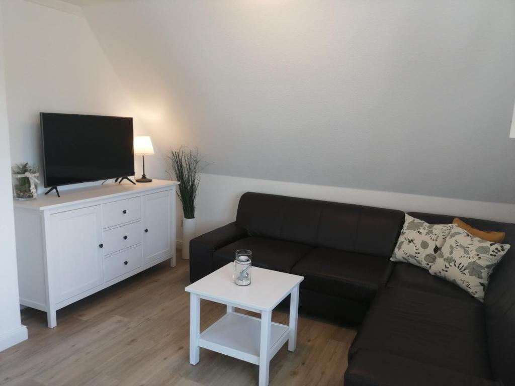 a living room with a black couch and a tv at Ostsee-Auszeit in Stakendorf