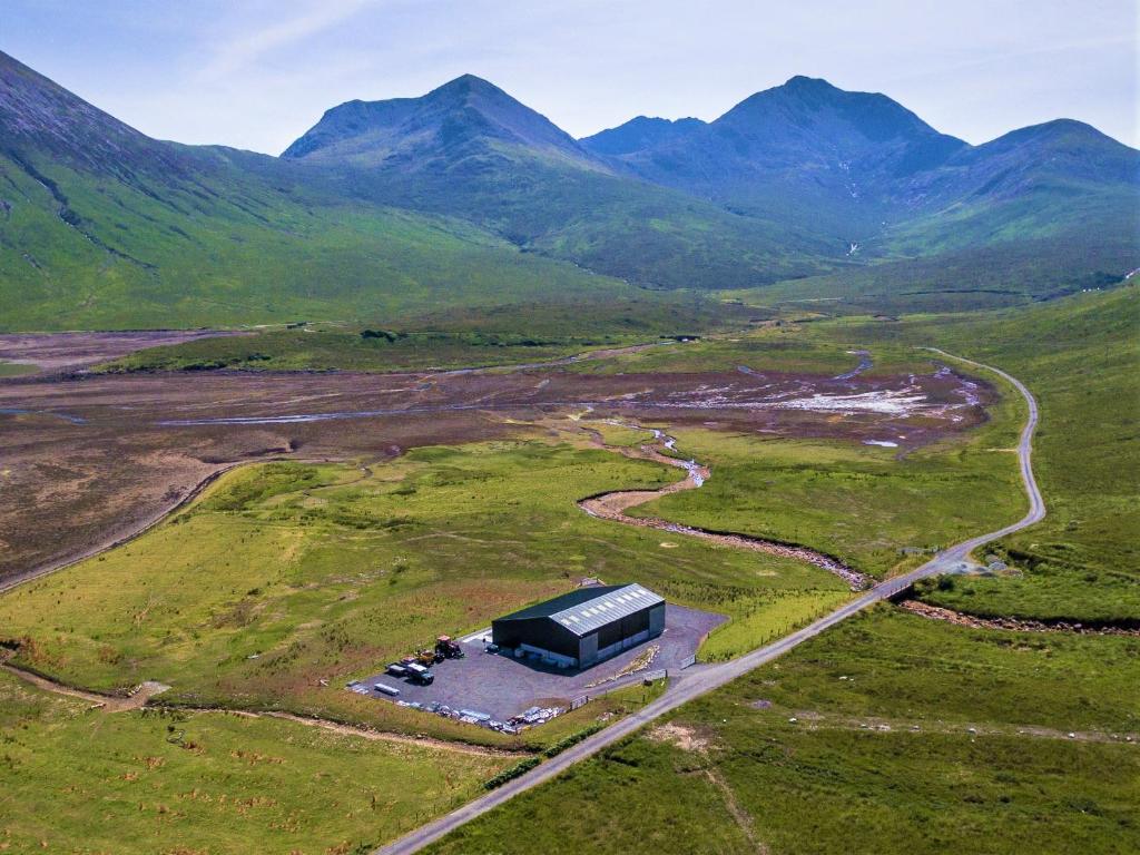 an aerial view of a building in a field with mountains at Kinloch Ainort Apartments in Luib