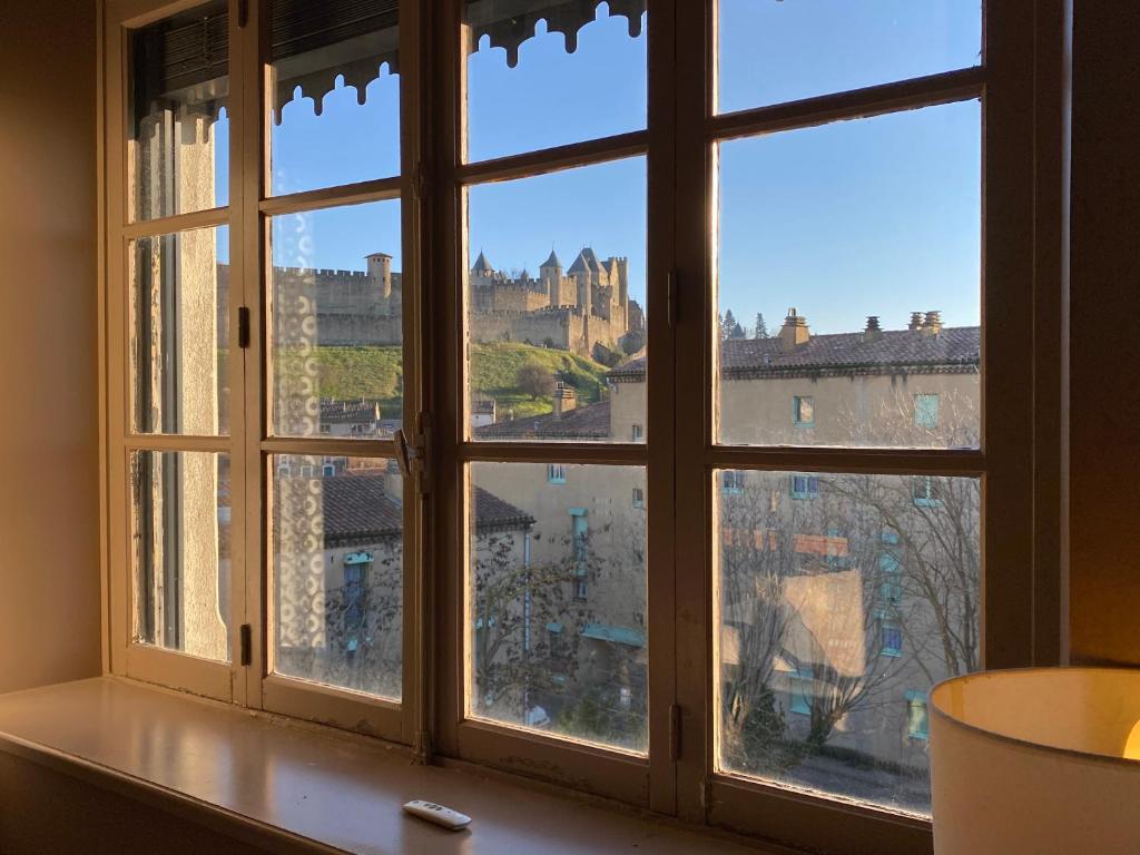 a window with a view of a city seen through it at Demeure Saint Louis Historic manor, City 700m, parking,A C,Clim,WIFI, heated pool, city view in Carcassonne