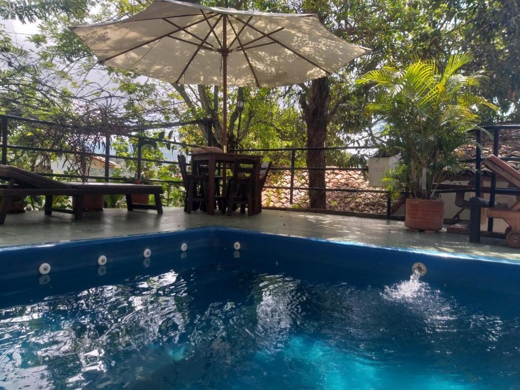 a pool with an umbrella and a table and chairs at Tinto Hostel in Barichara