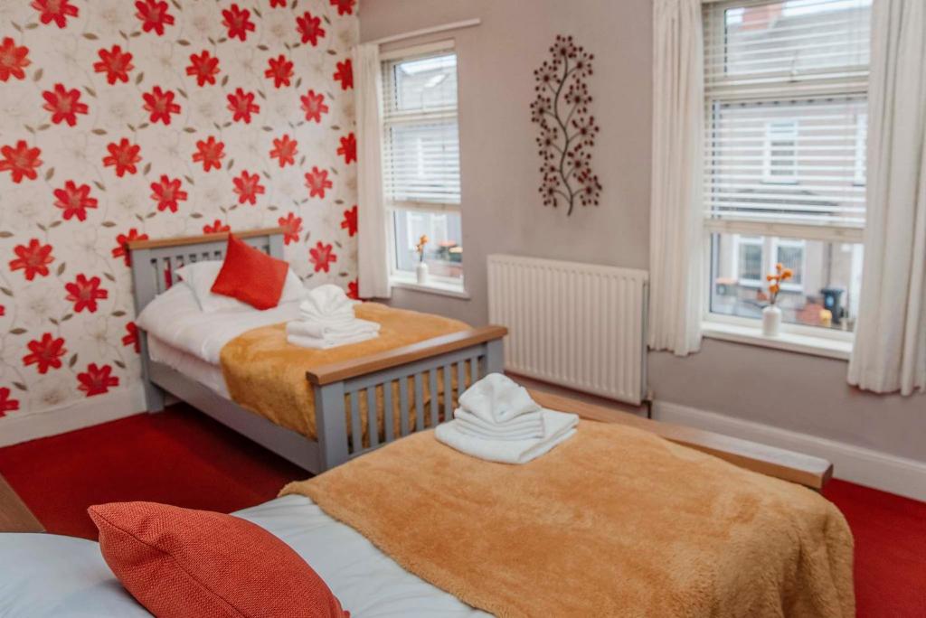 a bedroom with two beds and two windows at Lennard House in Newport
