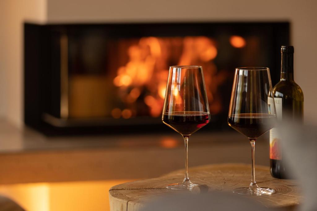two glasses of wine on a table in front of a fireplace at Wald Lounge in Oberstaufen