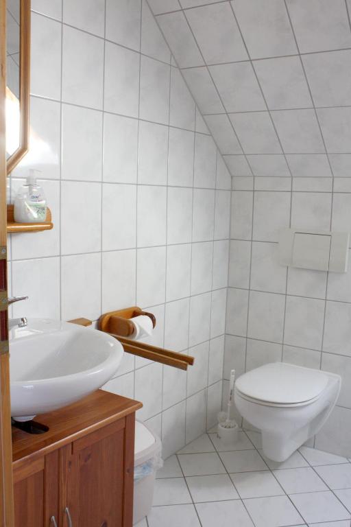 a white bathroom with a toilet and a sink at Pension Landhaus Teichgraf in Wolgast