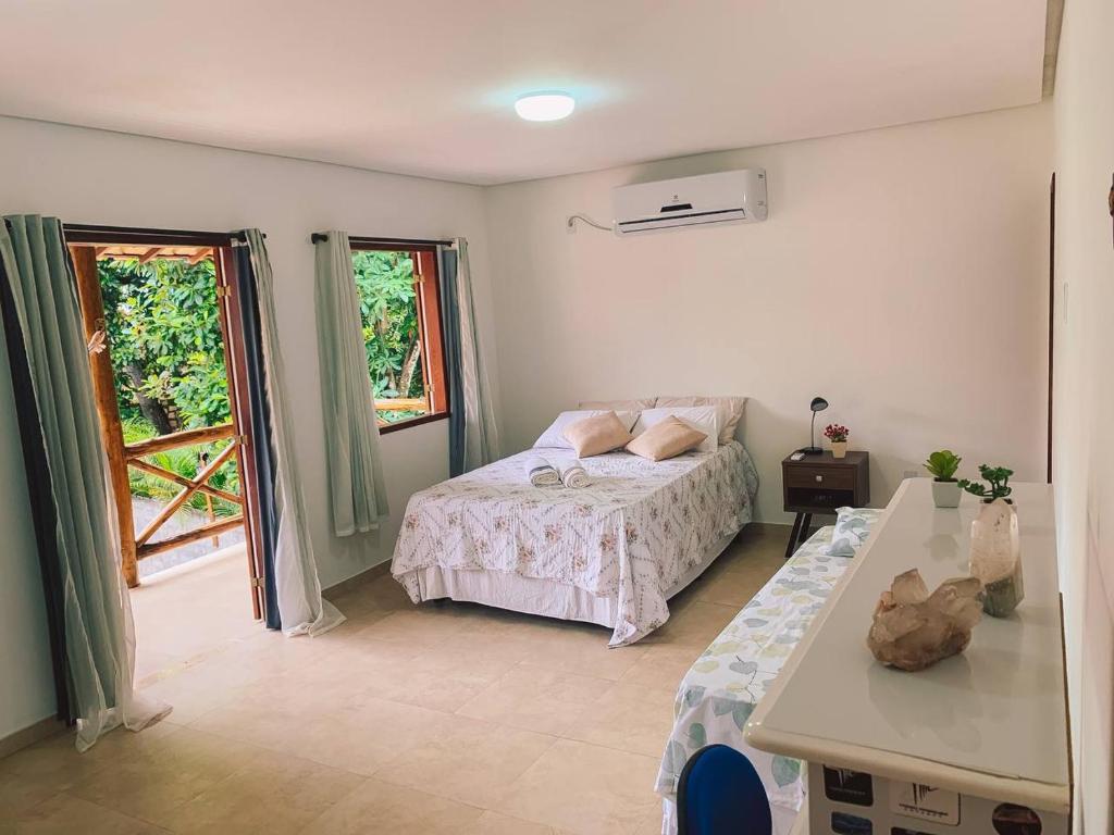 a bedroom with a bed and a table and windows at Casa Laranja Lençóis - BA in Lençóis