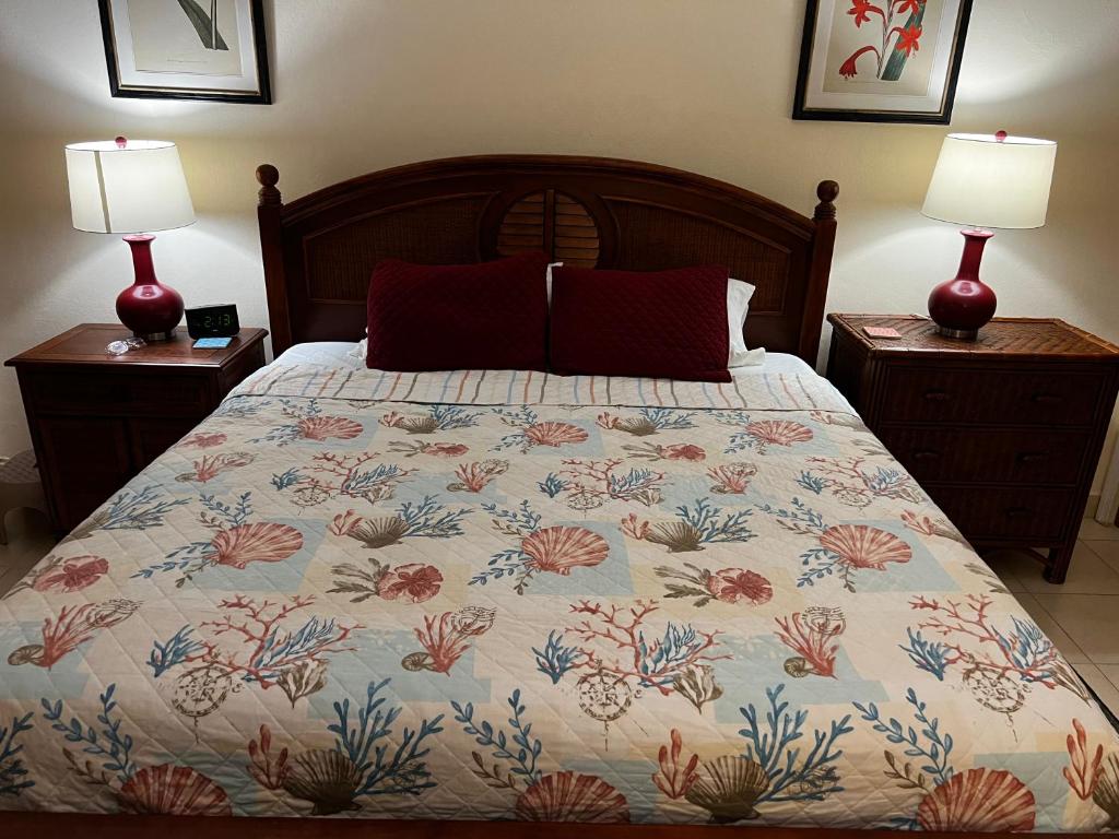 a bedroom with a bed with a floral bedspread and two lamps at Sweet Serenity St Croix USVI in Christiansted