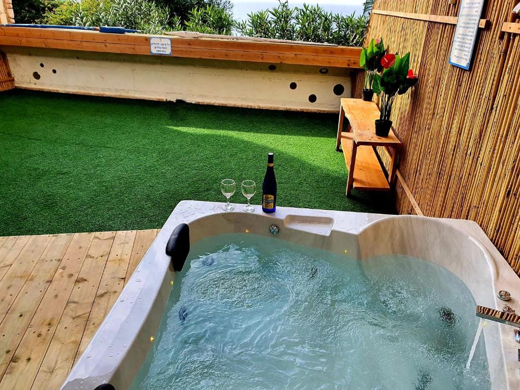 a hot tub with a bottle of wine in a backyard at סוויטת כוכב הים ומרפסת גן מול גלי הים ומדרגות ישר לחוף העונות in Netanya