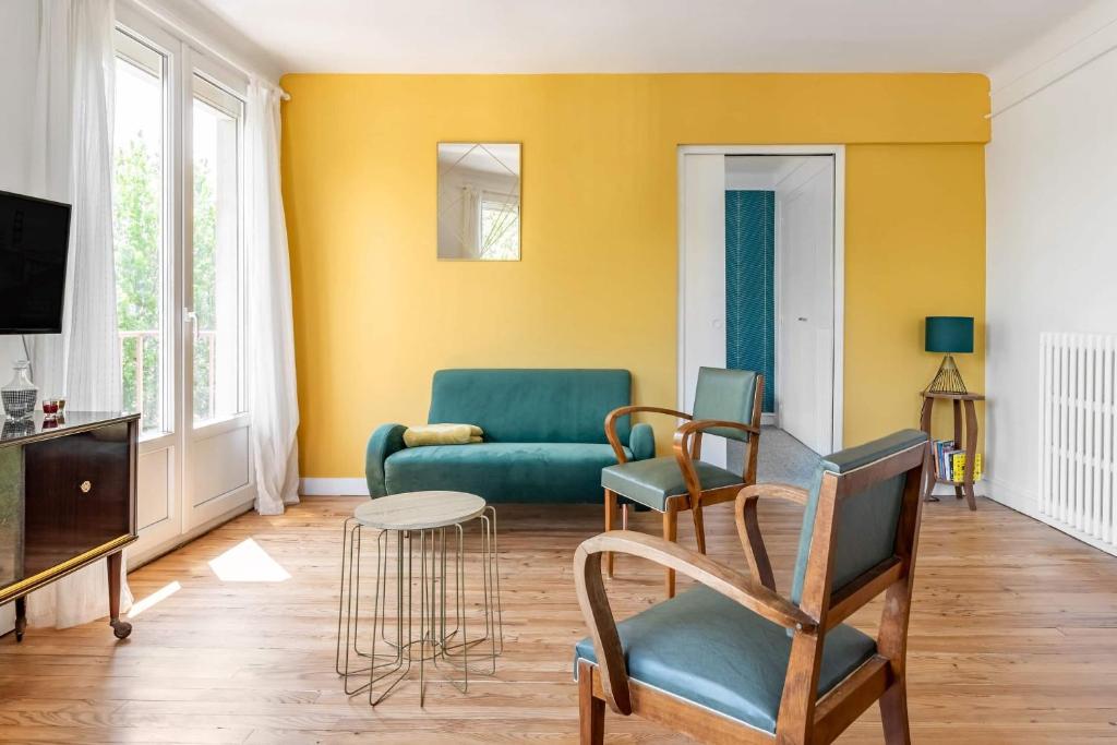 uma sala de estar com um sofá verde e cadeiras em Bel appartement avec garage sur l'île de Nantes em Nantes
