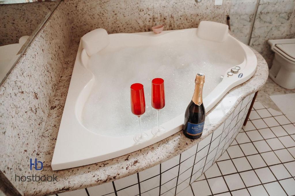 a bath tub with a bottle of champagne and two red candles at Casarão do Bosque a 200 m da praia | ROUR218 in Rio das Ostras