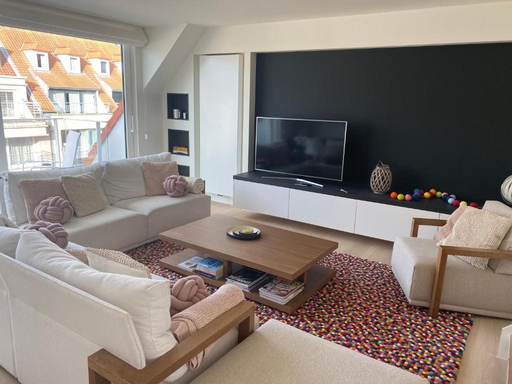 a living room with a couch and a tv at Ghibli - Duplex with parking in Knokke-Heist