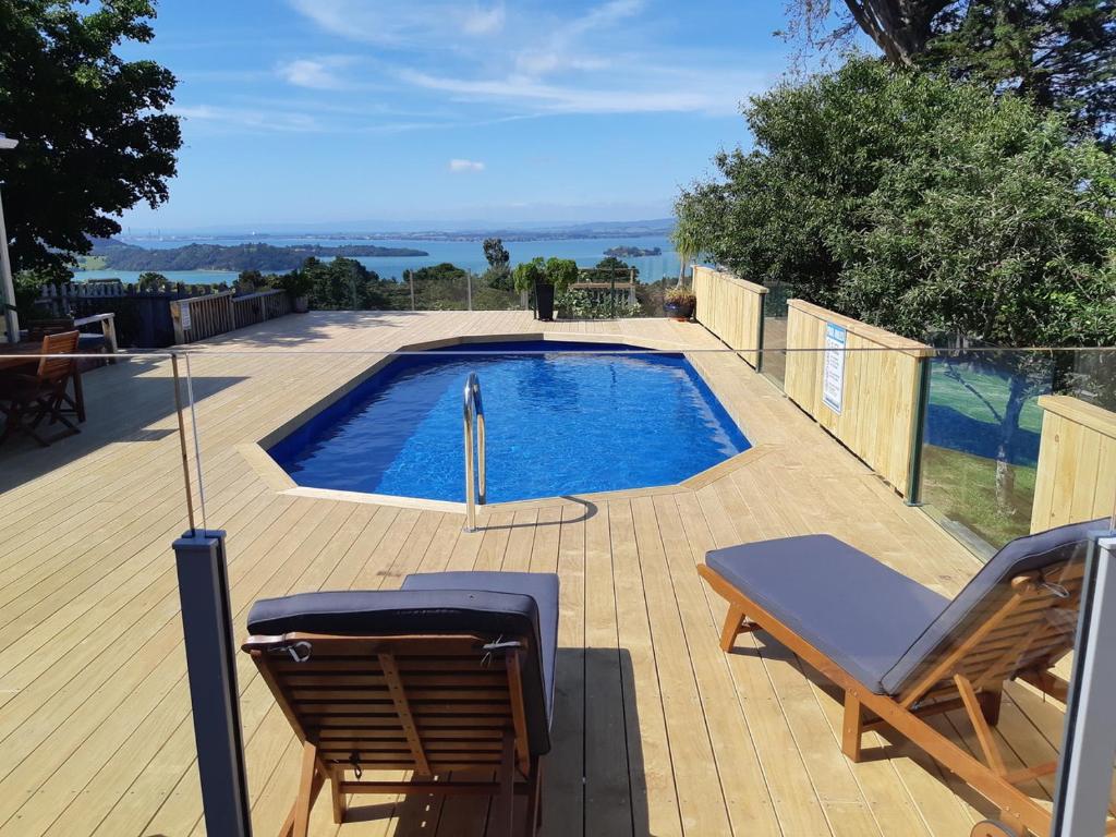 a swimming pool with two chairs and an umbrella at Kauri Villas in Parua Bay