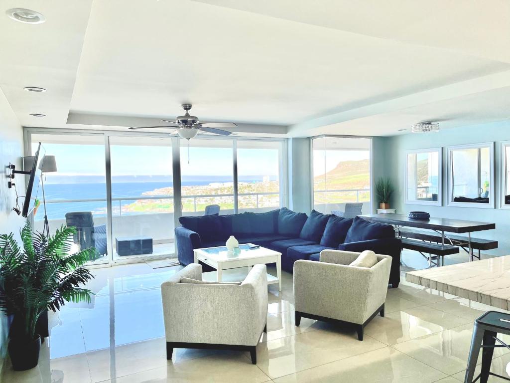 uma sala de estar com um sofá azul e cadeiras em Beachfront Condo close Puerto Nuevo, Papas, and Valle de Guadalupe em Rosarito