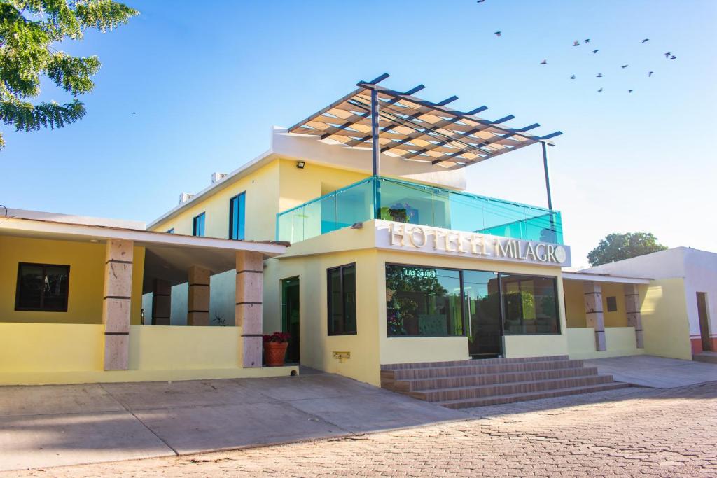 un bâtiment jaune avec un panneau en haut dans l'établissement Hotel EL MILAGRO, à El Fuerte