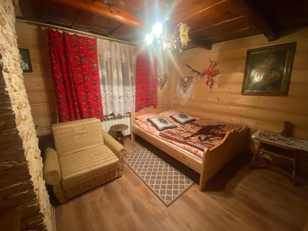 a bedroom with a bed and a chair in a room at Góralskie Pokoje in Witów