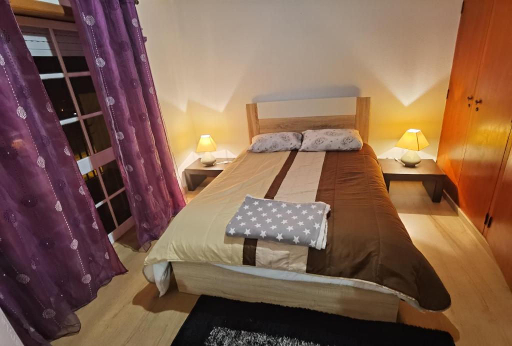 a bedroom with a large bed with purple curtains at Góis - Belas Vistas na N2 - AL in Góis