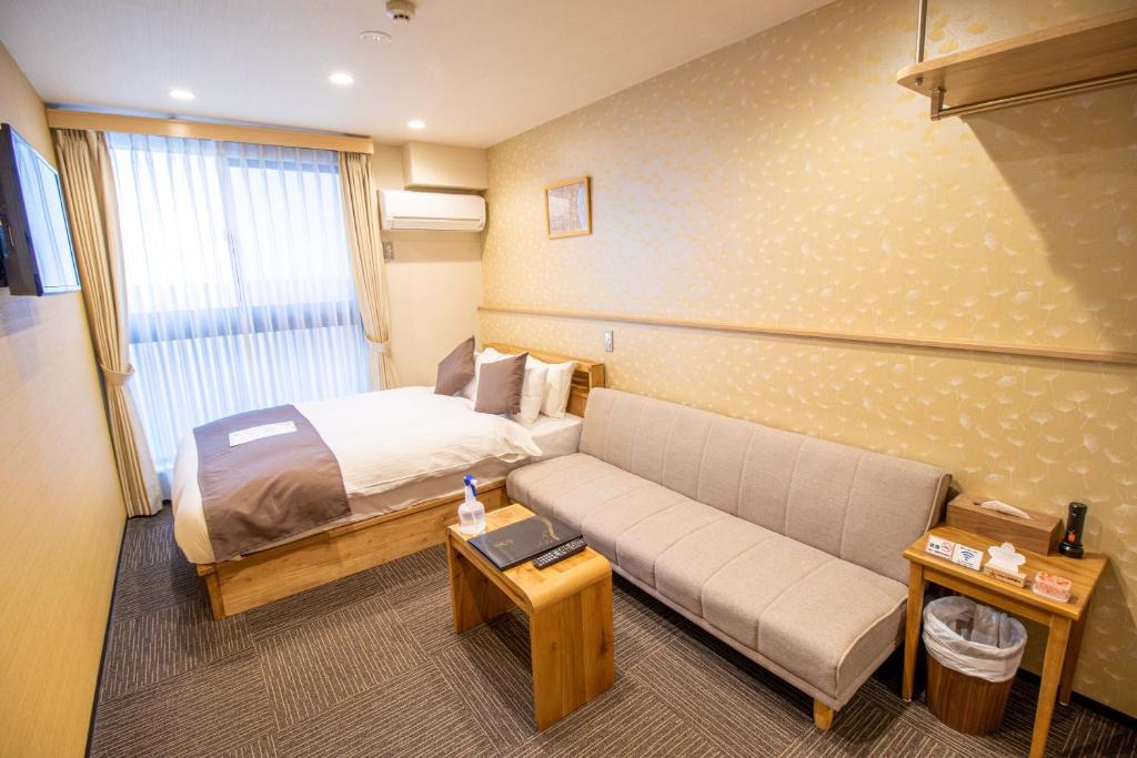 a hotel room with a bed and a couch at Stay SAKURA Kyoto Shijo Karasuma in Kyoto