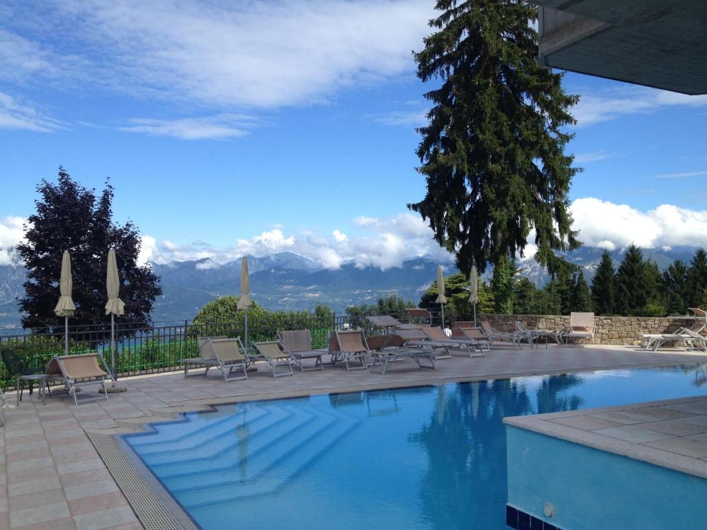 a swimming pool with chairs and a view of mountains at Albergo Sole in San Zeno di Montagna