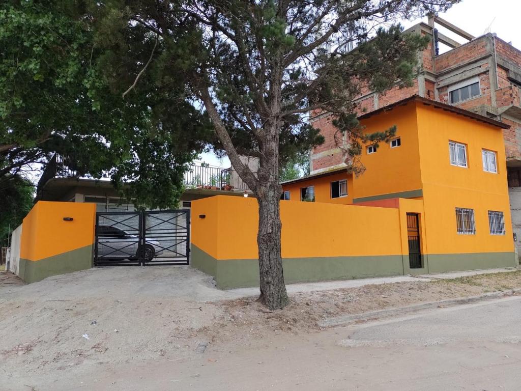 Una casa amarilla con un árbol delante. en Don Pocho en Mar de Ajó